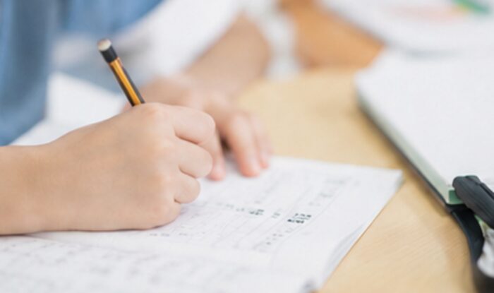 鉛筆でノートに書き込む子どもの手元（イメージ）